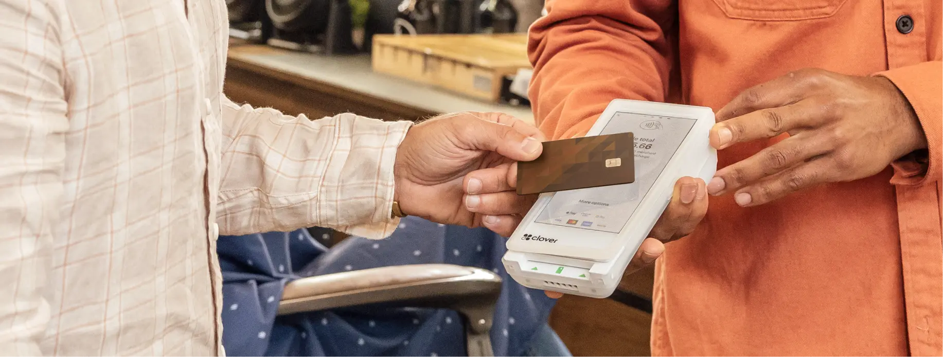 A barber holding the Clover Flex handheld POS system while a client completes their transaction